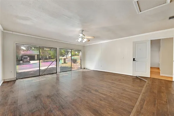 a view of an empty room with wooden floor and a window