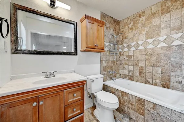 a bathroom with a granite countertop toilet sink and mirror