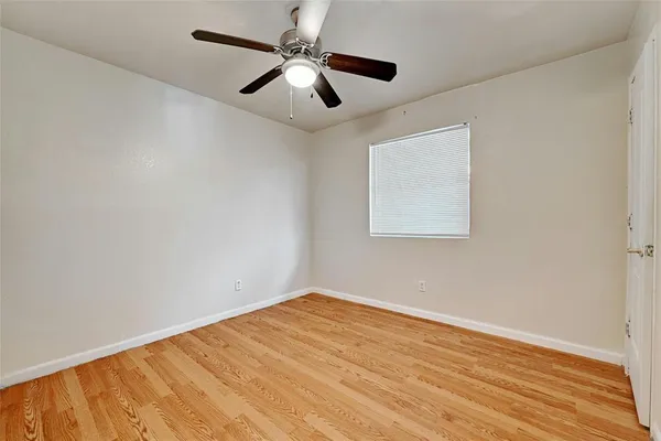 an empty room with wooden floor and ceiling fan
