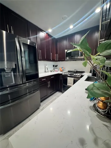 a kitchen with kitchen island granite countertop a sink a stove a refrigerator and a cabinets