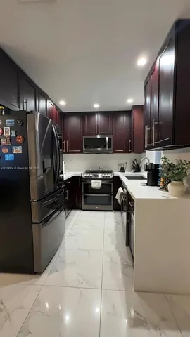 a kitchen with stainless steel appliances kitchen island granite countertop a sink refrigerator and cabinets