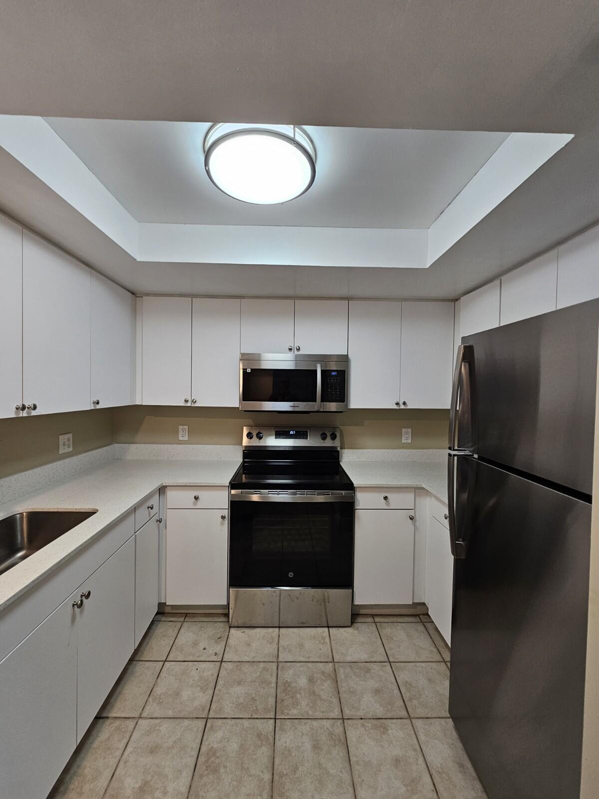 4191 Haverhill Road, Unit 408 West Palm Beach, FL 33417 - Photo 3 of 22 a kitchen with a stove a refrigerator and a sink