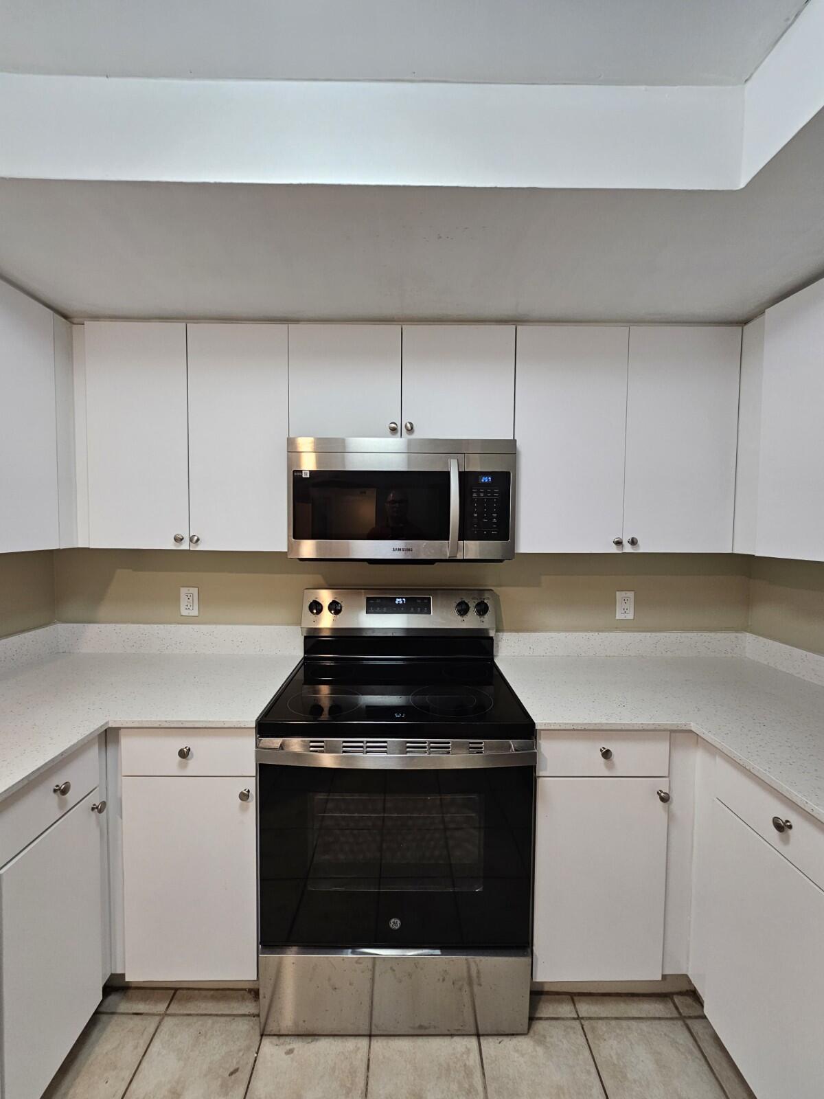 4191 Haverhill Road, Unit 408 West Palm Beach, FL 33417 - Photo 4 of 22 a kitchen with white cabinets and black appliances
