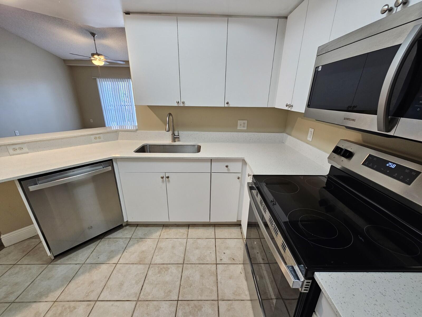 4191 Haverhill Road, Unit 408 West Palm Beach, FL 33417 - Photo 5 of 22 a kitchen with a sink stove and cabinets