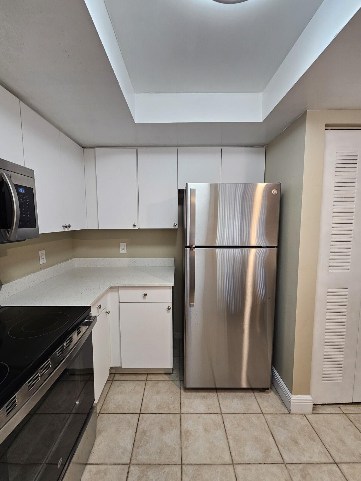 4191 Haverhill Road, Unit 408 West Palm Beach, FL 33417 - Photo 6 of 22 a kitchen with a refrigerator and a stove top oven