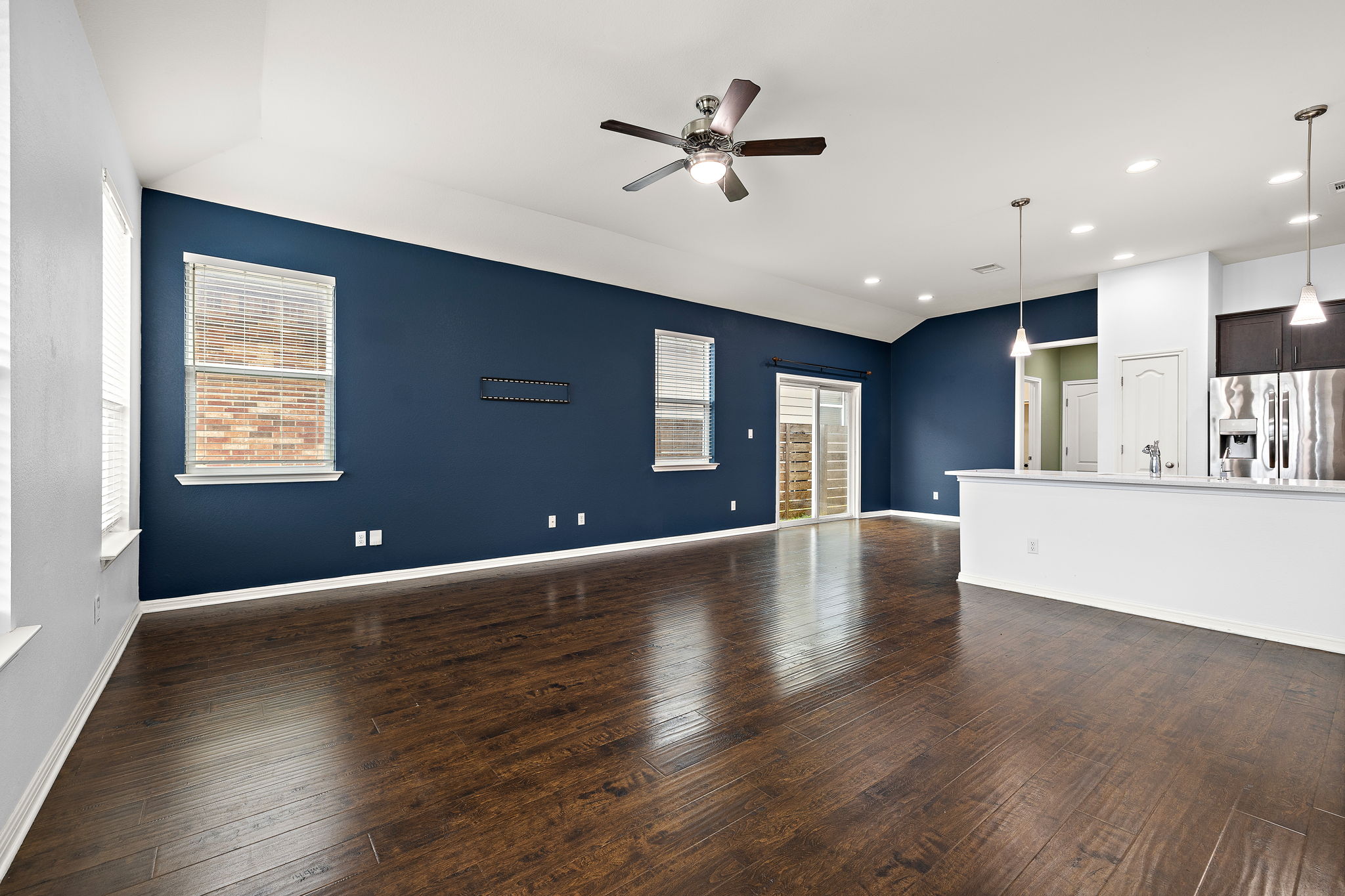 706 Coconut Grove Street Pflugerville, TX 78660 - Photo 4 of 23 Step into a bright and spacious living room where large windows fill the space with natural light and warm wood floors create a cozy place to relax.