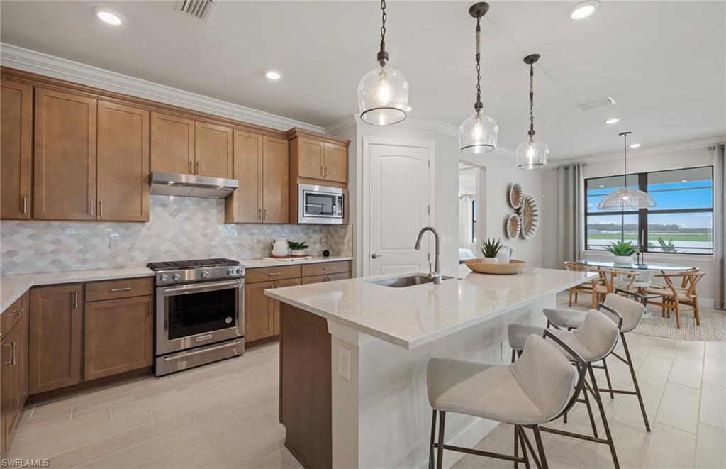 20498 Pebble Gln Drive Estero, FL 33928 - Photo 32 of 46 a kitchen with stainless steel appliances kitchen island granite countertop a sink a stove a dining table and chairs