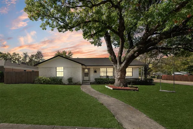 a front view of a house with a garden and trees