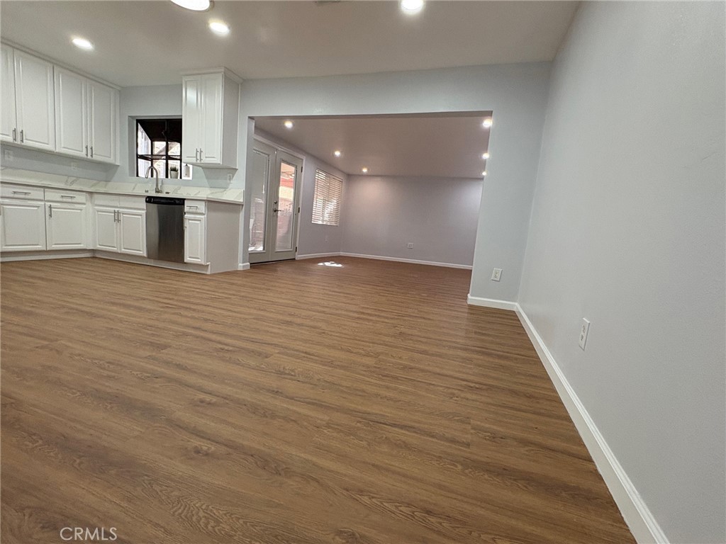 20730 Community Street Winnetka, CA 91306 - Photo 7 of 12 an empty room with wooden floor and kitchen view