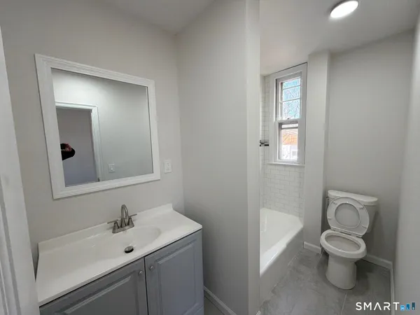 a bathroom with a toilet sink vanity and mirror