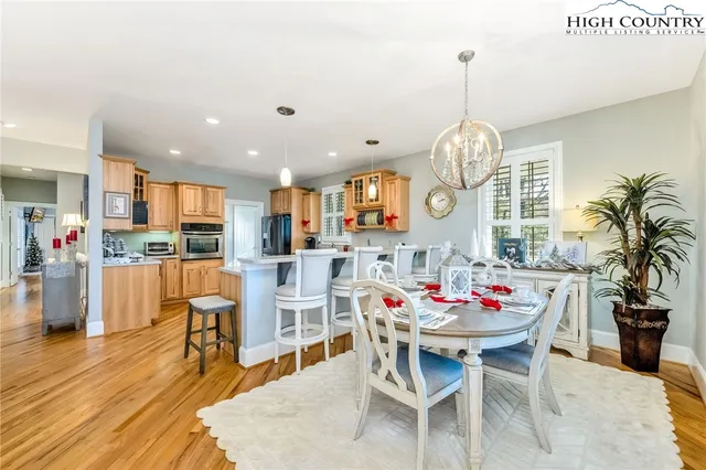 a dining room with chandelier and wooden floor