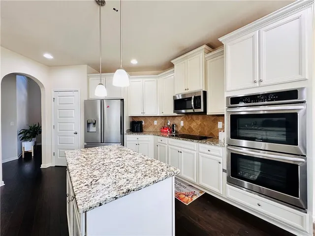 a kitchen with stainless steel appliances kitchen island granite countertop a stove top oven a refrigerator and a kitchen island