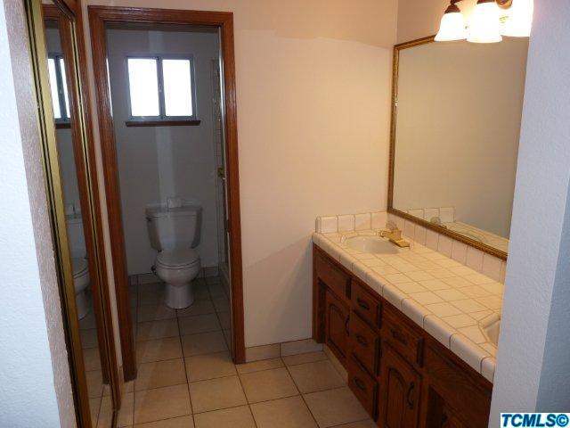 733 South Anderson Road Exeter, CA 93221 - Photo 13 of 17 a bathroom with a granite countertop sink toilet and mirror