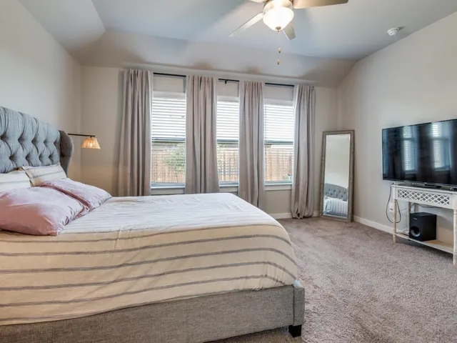 a spacious bedroom with a large bed and a chandelier fan