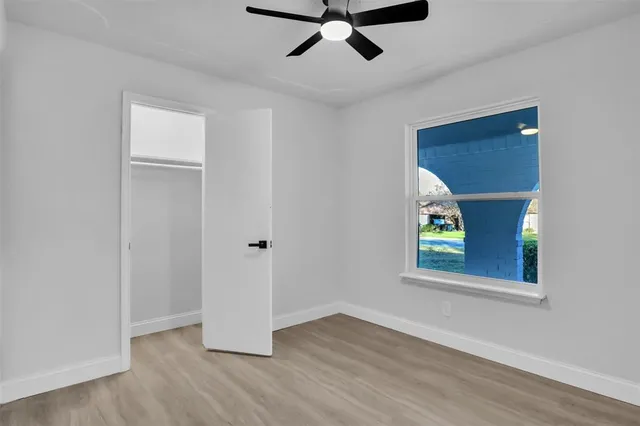 a view of an empty room with a window and wooden floor