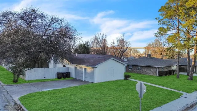 a view of house with a big yard potted plants and large tree