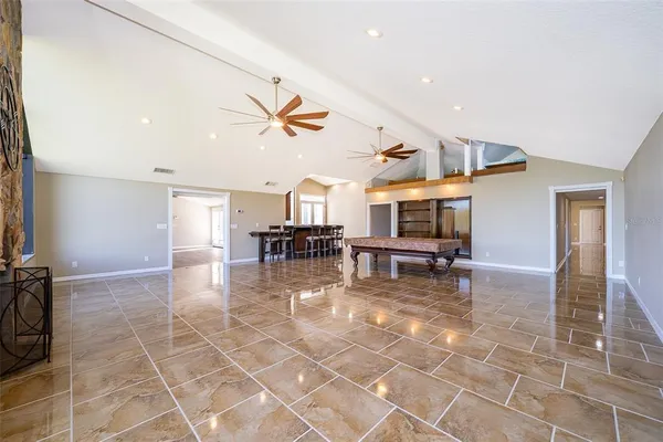 an empty room with wooden floor ceiling fan and windows