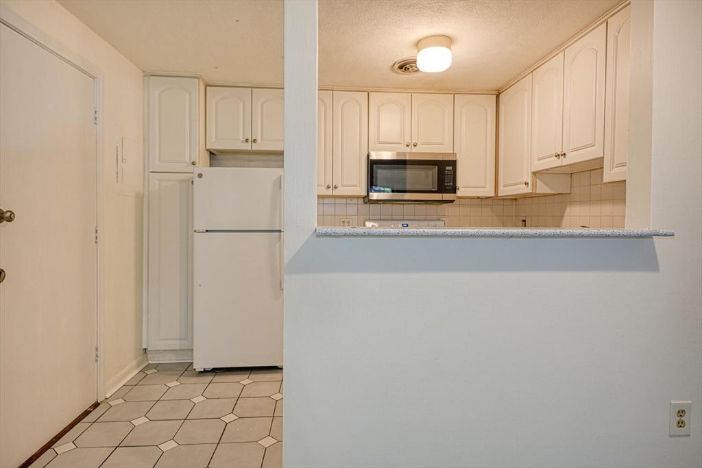 1323 Worcester Road, Unit 1E Framingham, MA 01701 - Photo 10 of 17 a kitchen with a refrigerator a stove top oven and white cabinets