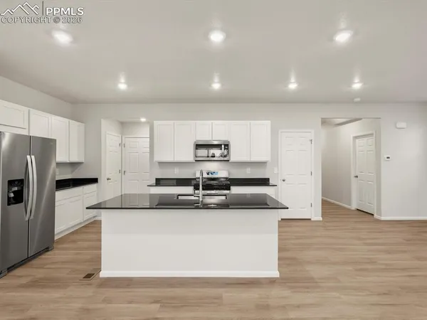 a large kitchen with stainless steel appliances granite countertop a large counter top and a stove top oven with wooden floor