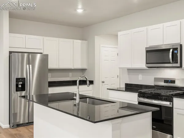 a kitchen with granite countertop a refrigerator and a sink