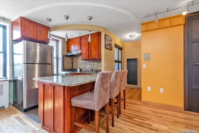 a kitchen with stainless steel appliances granite countertop a refrigerator a oven a sink dishwasher and a dining table with wooden floor