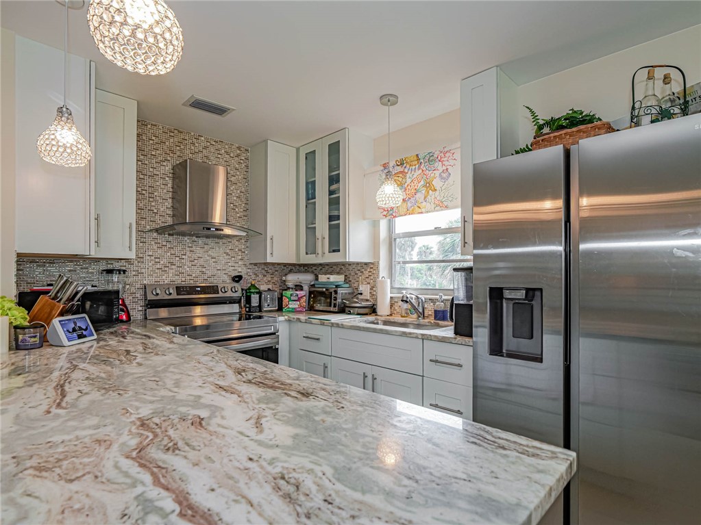 a kitchen with stainless steel appliances granite countertop a refrigerator a stove and a sink with dishwasher