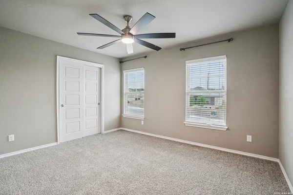 an empty room with chandelier fan and windows