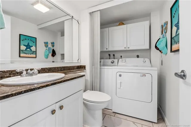 a bathroom with a granite countertop sink and a washing machine