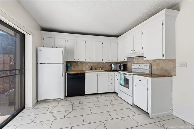 a kitchen with granite countertop white cabinets and stainless steel appliances