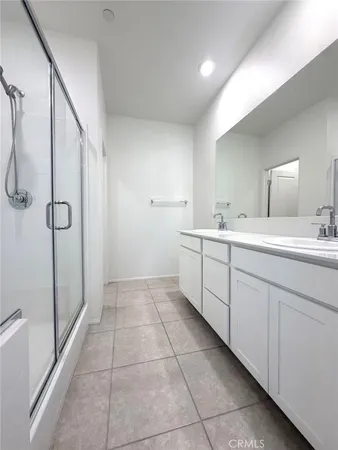 a spacious bathroom with a double vanity sink a mirror and a shower