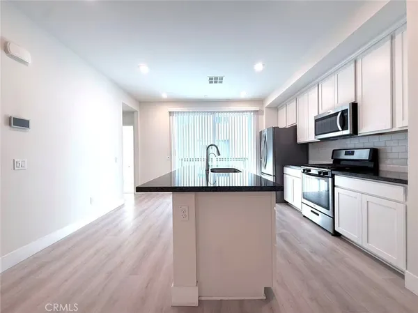 a large kitchen with stainless steel appliances granite countertop a stove a sink and a microwave