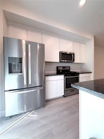 a kitchen with granite countertop a refrigerator and a stove top oven