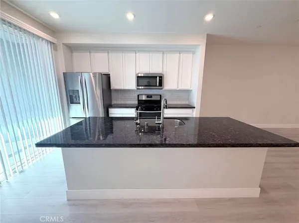 a kitchen with kitchen island a sink a stove a microwave and cabinets