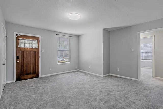 a view of an empty room with closet and a window