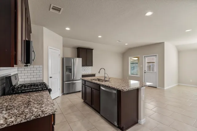 a kitchen with stainless steel appliances granite countertop a sink stove and refrigerator