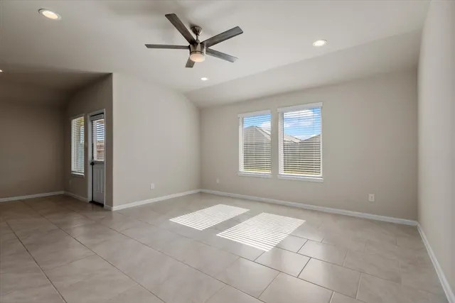 en empty room with windows and ceiling fan