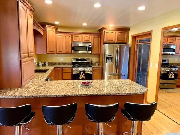 a kitchen with stainless steel appliances granite countertop a kitchen island a stove a table and chairs