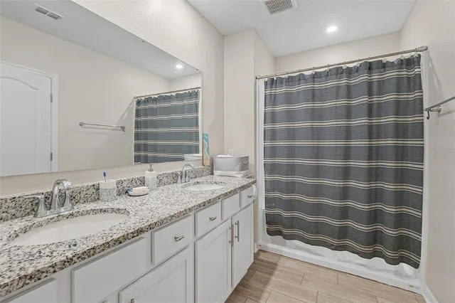 a bathroom with a granite countertop double vanity sink and mirror