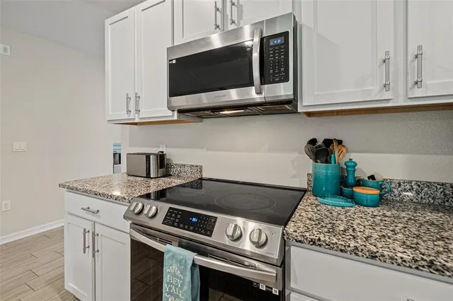 a kitchen with stainless steel appliances granite countertop white cabinets a stove top oven and granite counter tops