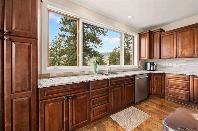 a kitchen with stainless steel appliances granite countertop wooden cabinets a sink and a window