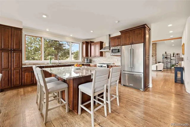 a kitchen with stainless steel appliances a dining table chairs refrigerator and a large window