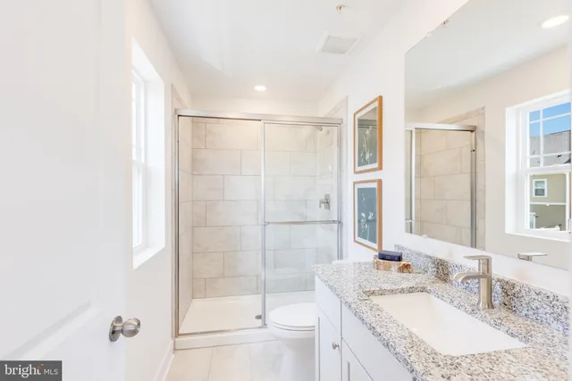 a bathroom with a granite countertop sink a toilet and shower