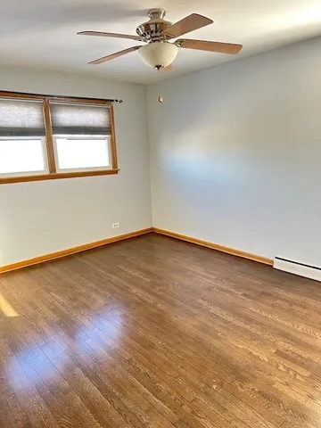 an empty room with wooden floor fan and windows
