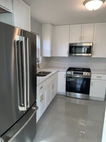 a kitchen with stainless steel appliances white cabinets and a refrigerator