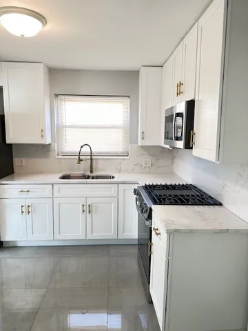 a kitchen with granite countertop white cabinets and white appliances