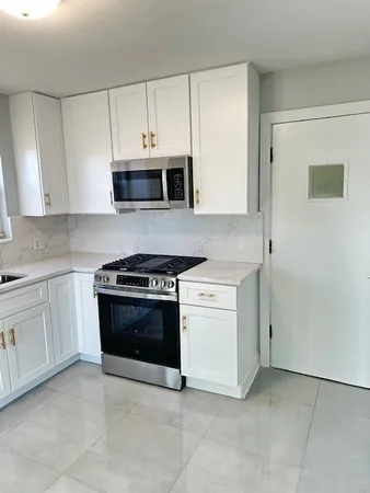 a kitchen with granite countertop white cabinets and stainless steel appliances