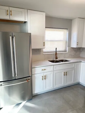 a kitchen with granite countertop white cabinets and refrigerator