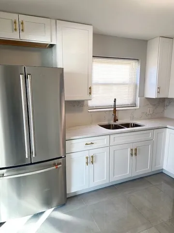 a kitchen with granite countertop white cabinets and refrigerator