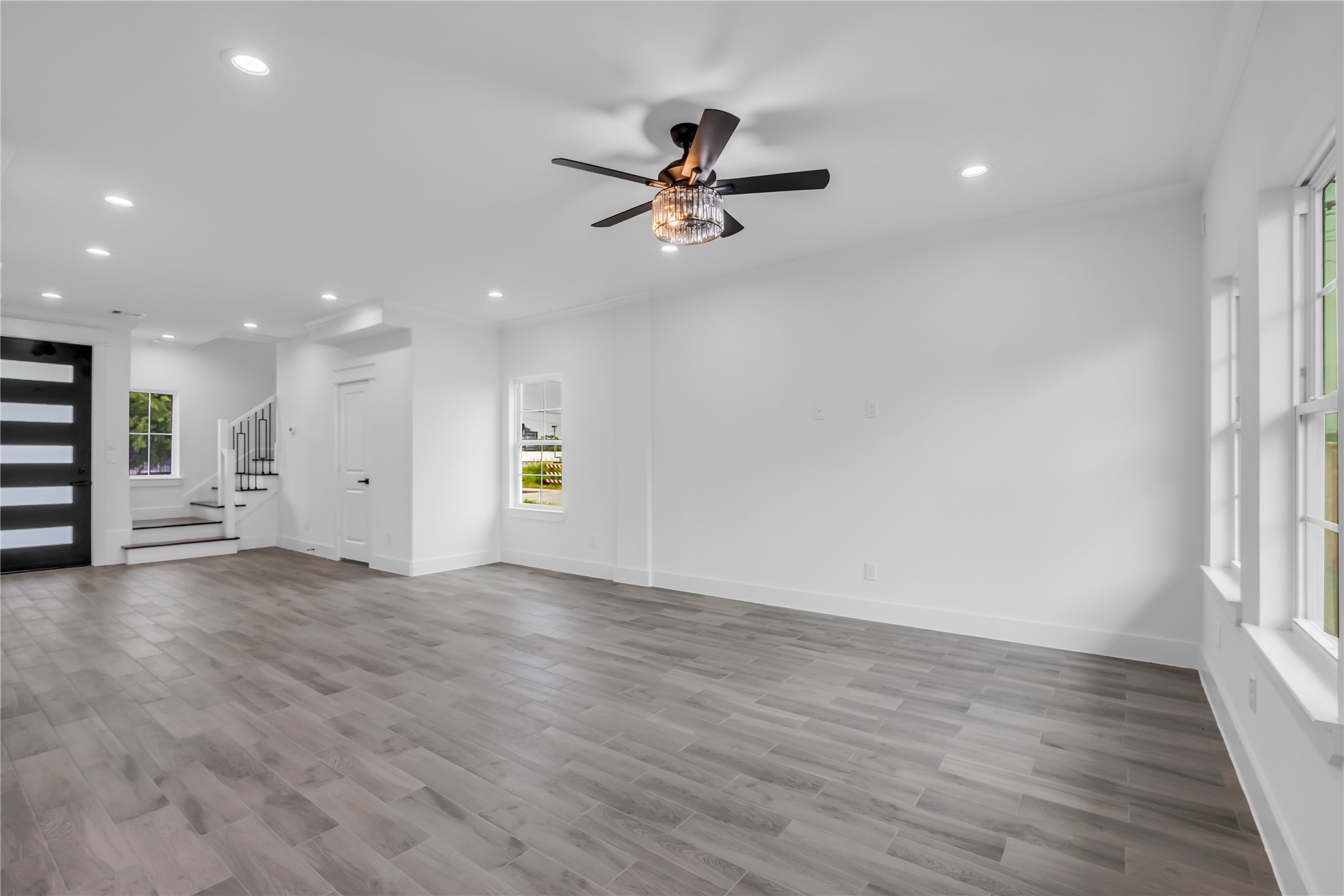3168 Golfcrest Houston, TX 77087 - Photo 15 of 30 This inviting living room boasts sleek wood flooring, abundant natural light from large windows, and a stylish ceiling fan, creating a perfect blend of comfort and elegance.