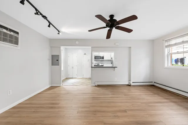 a view of empty room with wooden floor and ceiling fan